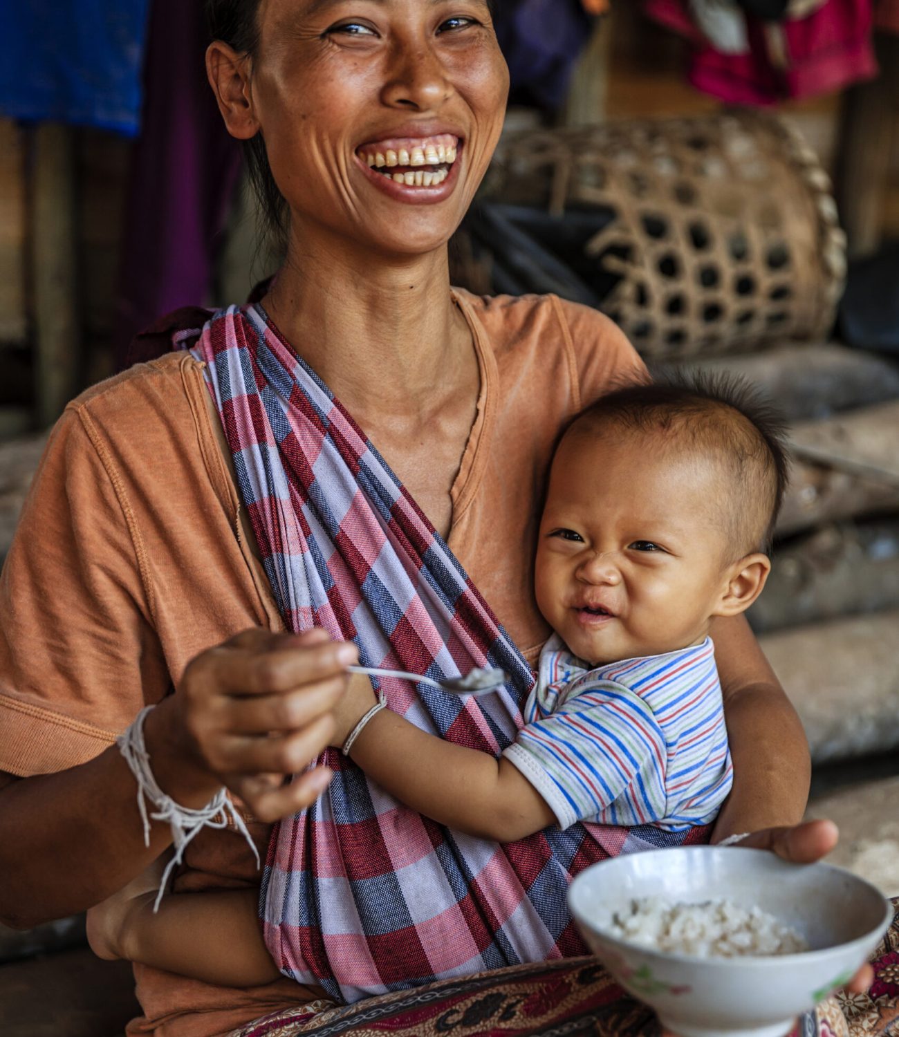 Laotian young mom feeding her baby boy in a village in Northern Laos